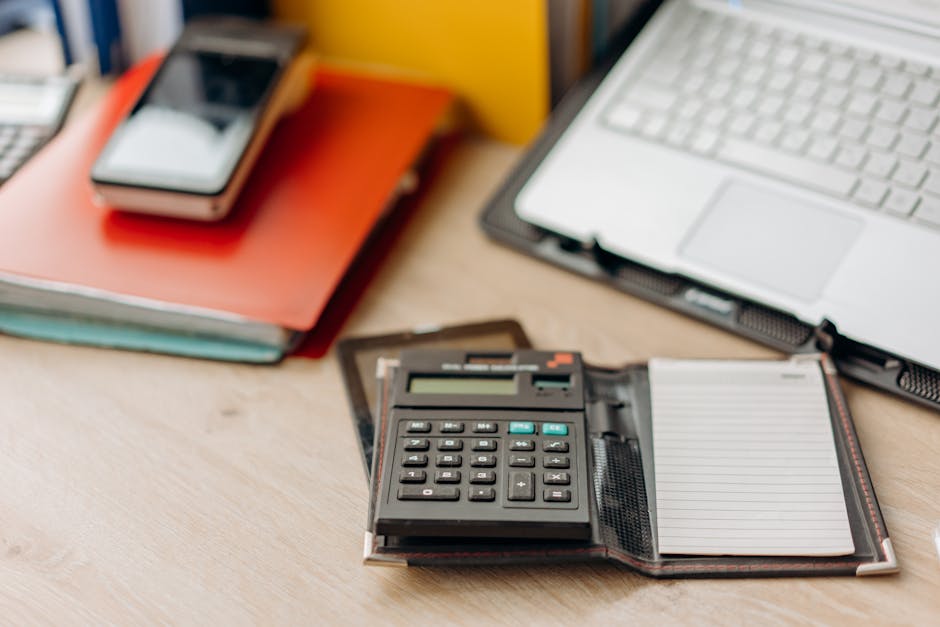 Organized workspace featuring a calculator, notepad, and laptop. Perfect for productivity themes.
